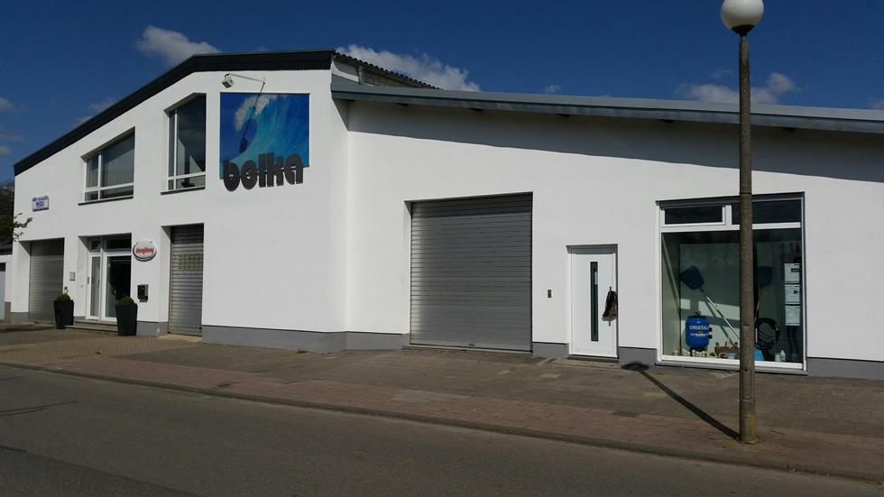 Ein modernes, weißes Gebäude mit blauer und grauer Fassade und Firmenschildern.