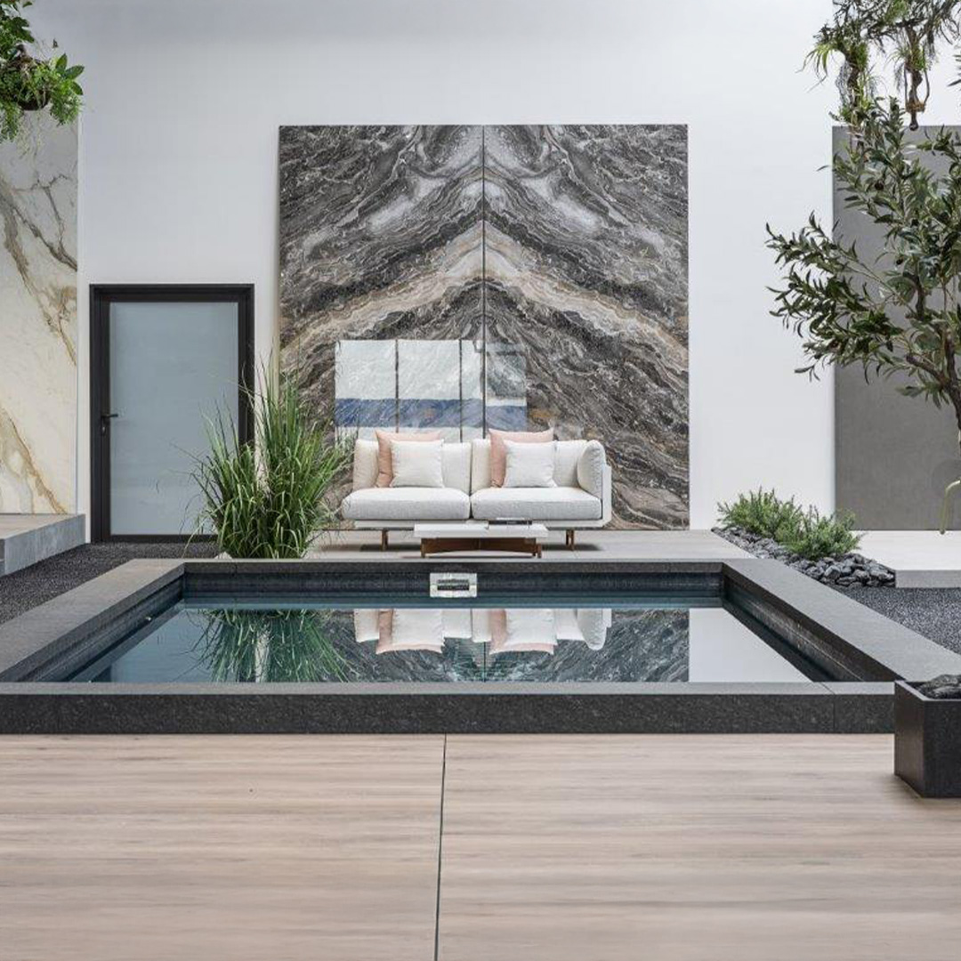 Moderner Innenhof mit elegantem Pool, beiger Couch und großen Marmortafeln im Hintergrund.