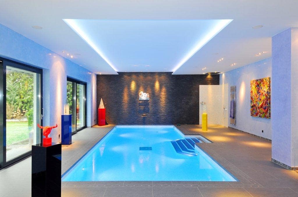 Luxuriöser Innenpoolraum mit bunten Kunstwerken, blauen Wänden und modernen Designelementen.