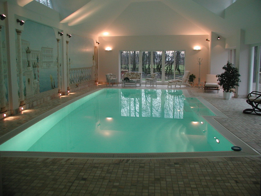 Ein eleganter Innenpool mit großen Fenstern, hellem Boden und einer Wandmalerei in Pastellfarben.
