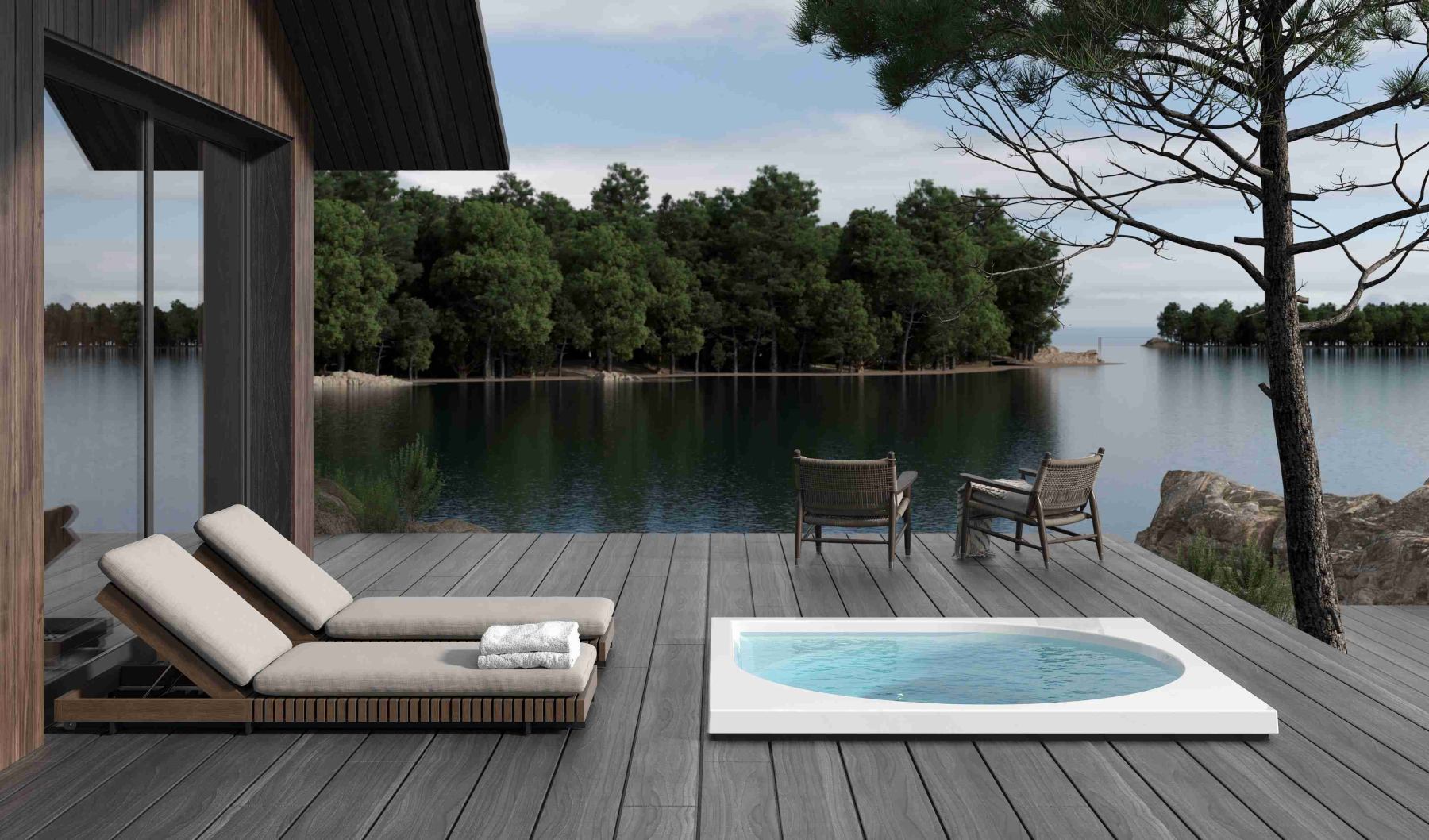 Moderne Terrasse mit zwei Liegen, Whirlpool, zwei Stühlen, Blick auf einen Wald und See im Hintergrund.