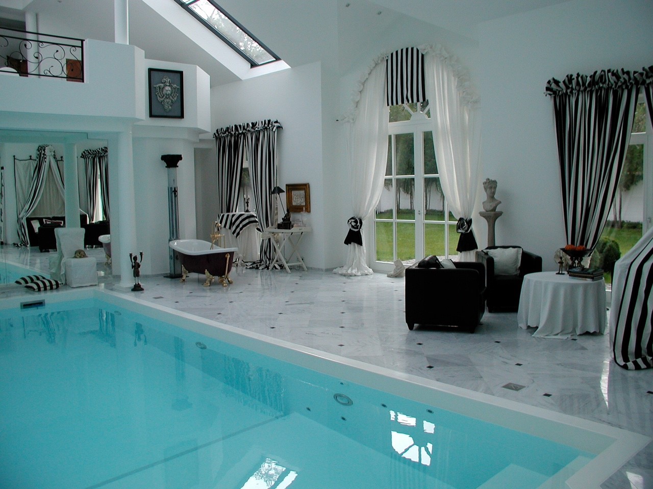 Luxuriöses Wohnzimmer mit Pool, schwarz-weißen Streifen, hohen Fenstern und eleganten Vorhängen.