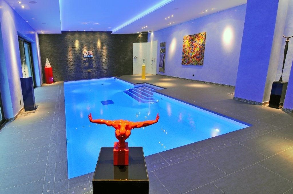 Innenpool mit blauer Beleuchtung, roter Skulptur im Vordergrund und bunte Kunst an der Wand.