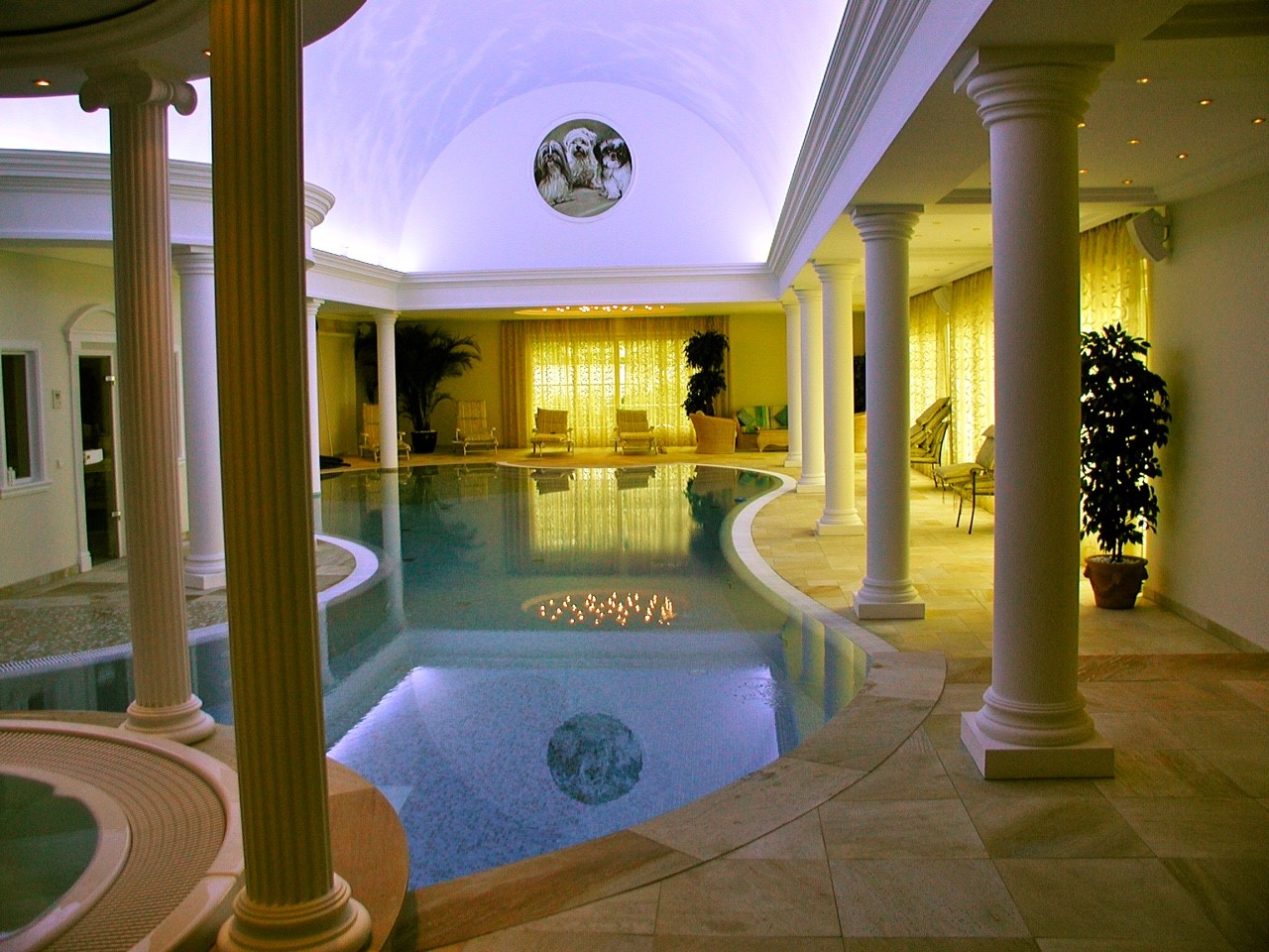 Luxuriöser Innenpool mit gewölbter Decke und eleganten Säulen, umgeben von reichlich Grünpflanzen.