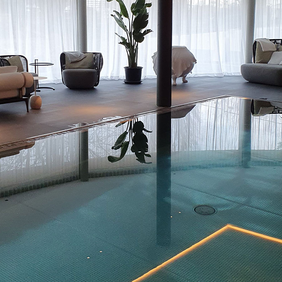 Eine elegante, moderne Lounge mit Pool und Pflanzen im Hintergrund.