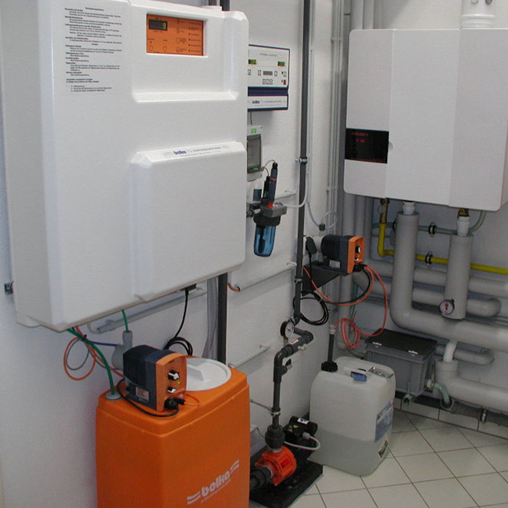 Weiß-orange technische Anlage mit Anzeigedisplays und Rohren in einem Industrieumfeld.