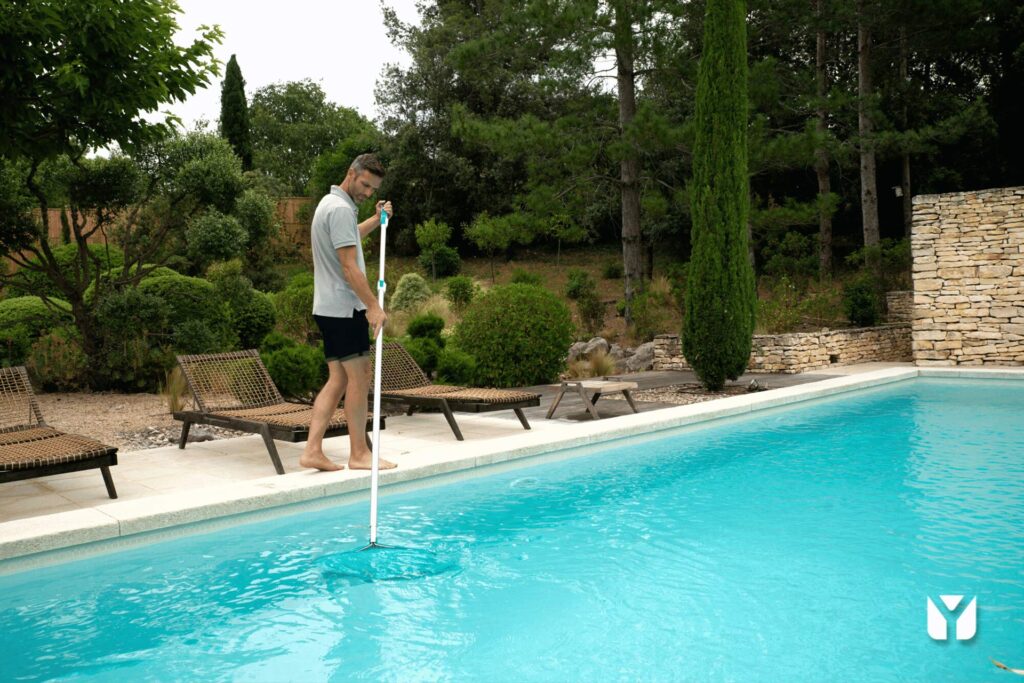 Ein Mann reinigen den Pool mit konzentrierter Ausdrücke, in einem Garten.
